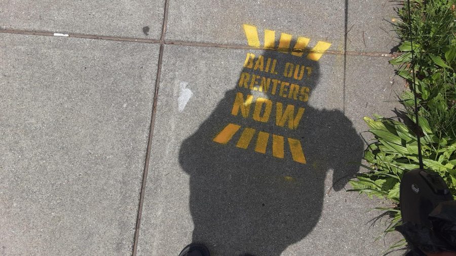 A passerby shelters the sidewalk sign from the sun. The signs of protest quietly appeared. 